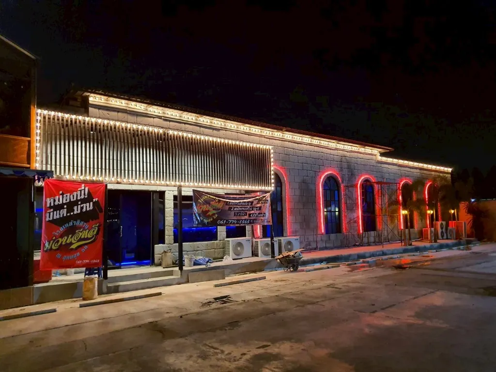 งานตกแต่งภายนอกร้านเหล้าอีสานผนังหินพร้อมไฟหลอดกลมและไฟนีออนสีแดง